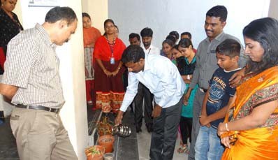 Guires leaders and families watering potted saplings at the campus entrance